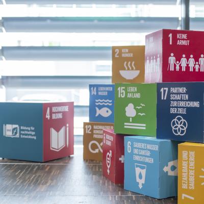 Farbig gestaltete Würfel mit Symbolen und Texten zu den 17 Zielen für nachhaltige Entwicklung (SDGs).