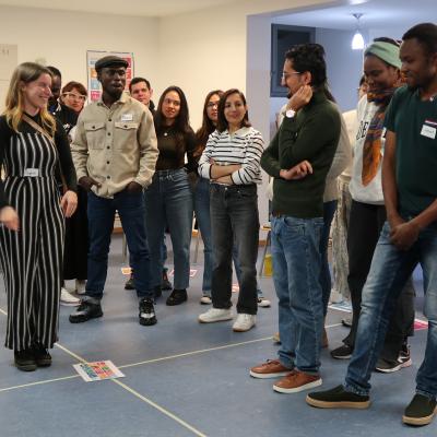 Eine Gruppe von Personen steht an einer Linie, die am Boden des Raumes gezogen ist. 