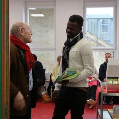 Am Eingang in einem raum stehen zwei Menschen und unterhalten sich angeregt miteinander. 