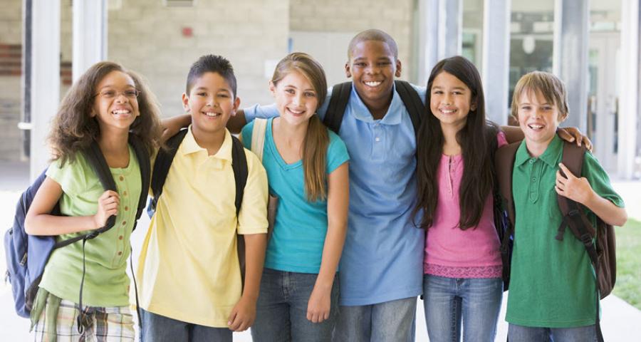 Gruppe von Schulkindern blickt lachend in die Kamera. 